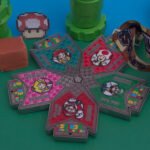 Assortment of colorful Super Smash Series medals with video game character designs.