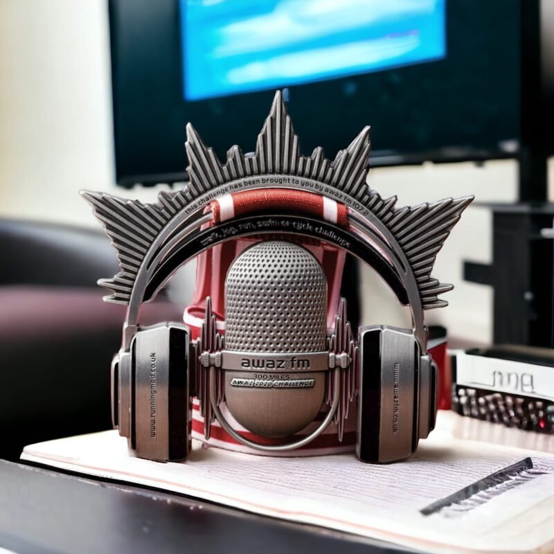 Innovative Awaz FM-themed microphone-shaped running medal with headphones and wings.