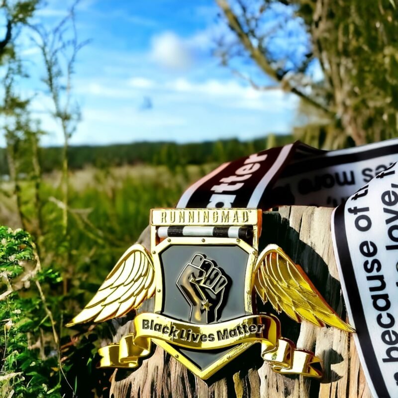 Black Lives Matter virtual challenge medal with wings, reflecting on surface with bokeh lights