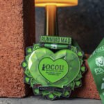 Green heart OCOU medal from Running Mad for the 100 Miles for Yemen, against an urban background.